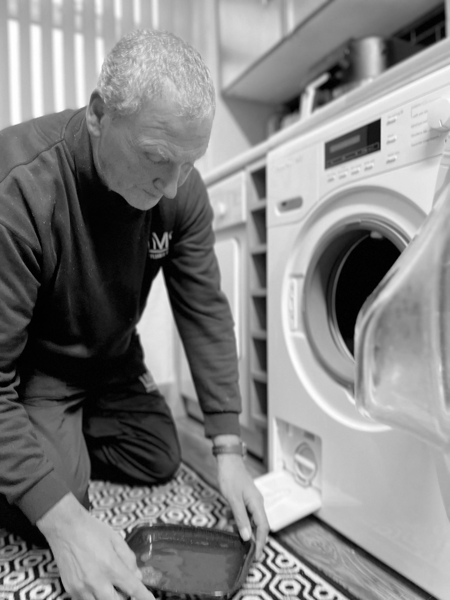 Close-up of an LMS Appliance Repairs engineer draining and repairing a washing machine